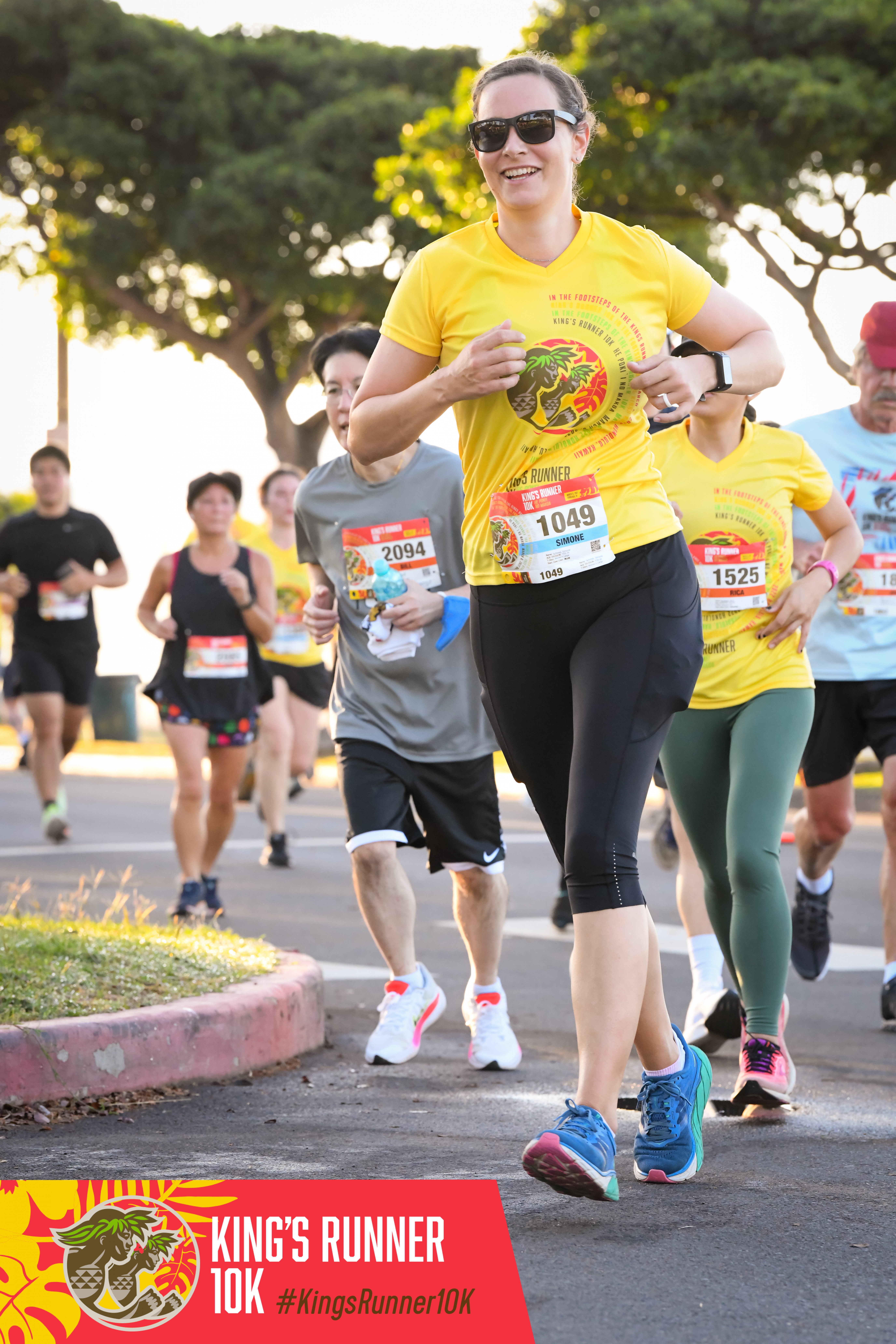 Simone Schmid jogging in the Kingʻs Runner 10k. Sheʻs smiling and wearing sunglasses.